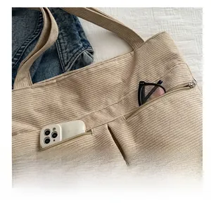 Detail shot of corduroy tote bag featuring two functional silver zipper front pockets