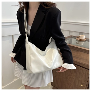 Detailed view of a white glossy minimalist tote bag shown in a professional lifestyle setting