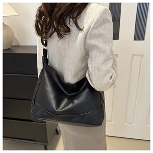 Detail of minimalist black leather hobo bag showing texture and slouchy drape style