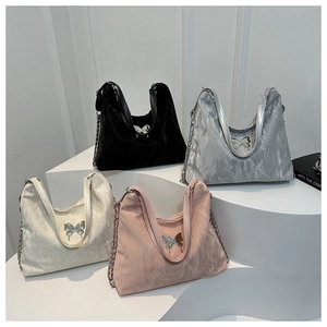 Detail of trendy hobo bags featuring metallic butterfly buckles and pleated fabric texture