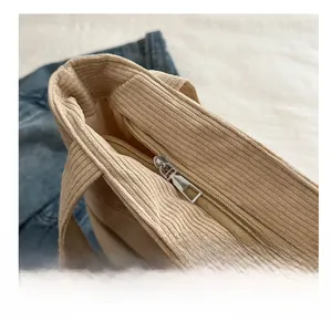 Detailed macro shot of a smooth silver zipper closure on a beige corduroy tote bag