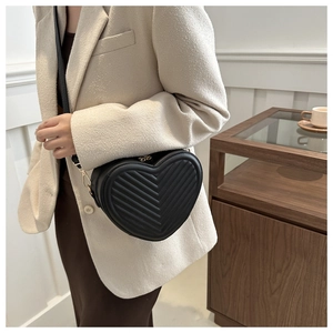 Close-up of black heart-shaped crossbody bag with elegant V-shaped quilted leather pattern