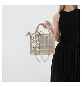 Close-up of quilted gold faux leather tote with chain strap and elegant silk scarf detail