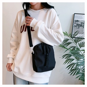 Detail of black nylon crossbody bag featuring a unique drawstring closure and white side hooks