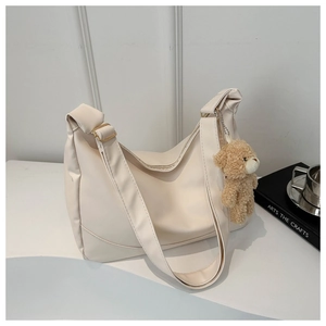 Detail of cream white half-moon shoulder bag with cute brown plush bear charm