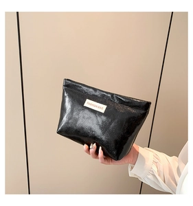 Detail of black glossy embossed leather toiletry bag with FASHION BAG label and zipper