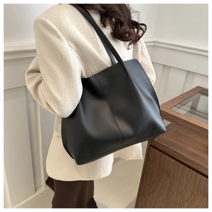 Model wearing a large black matte PU leather tote bag with elegant minimalist French style