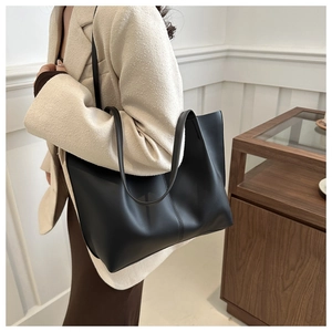Detail of minimalist black matte faux leather tote bag with vertical stitching on shoulder strap