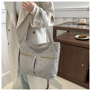 Detail of light gray corduroy tote bag with front zippers and textured fabric detail