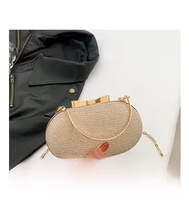 Close-up of champagne gold woven evening clutch with a gold bow metal clasp and chain