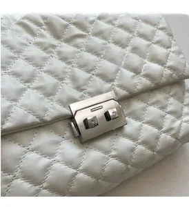 Close-up of elegant white quilted leather with silver metal lock on shoulder bag