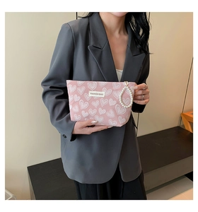 Detail of pink canvas cosmetic bag with heart textures and pearl handle accessory
