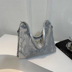 Silver pleated shoulder bag with metallic butterfly accent and chain strap in Y2K style