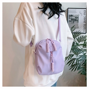 Detail showing lavender nylon crossbody bag with braided zipper pulls and waterproof fabric