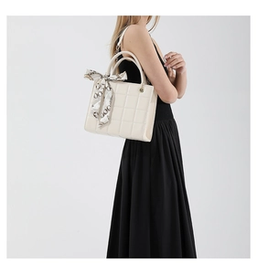 Close-up of off-white quilted handbag with a stylish geometric print silk scarf handle