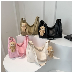 Detailed view of four solid color leather tote bags with cute plush bear charms