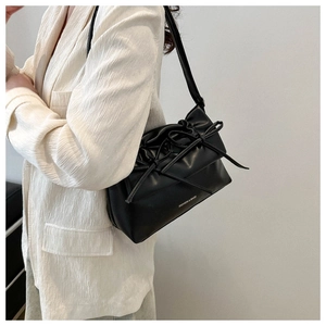 Detail of soft black faux leather shoulder bag with decorative bow and fashion lettering