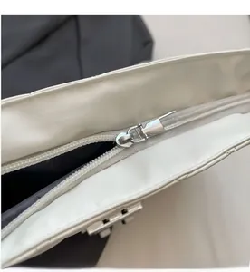 Detail of smooth silver zipper hardware on white quilted faux leather bag with black lining