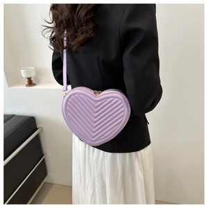 Detailed view of the purple heart-shaped crossbody bag with quilted V-pattern stitching