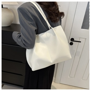 Detail view of large white minimalist tote bag with soft leather texture on a shoulder strap