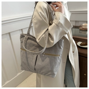 Detail of grey corduroy tote bag featuring two front zipper pockets and minimalist design