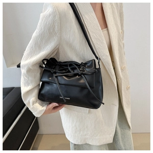 Close-up of black ruched shoulder bag with bow detail and white fashion text logo