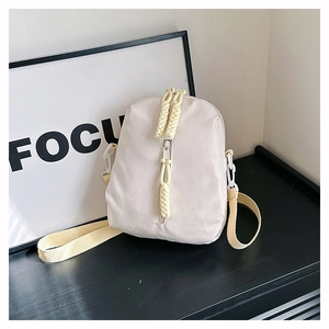 Detail view of cream-white nylon crossbody bag featuring hand-woven zipper puller