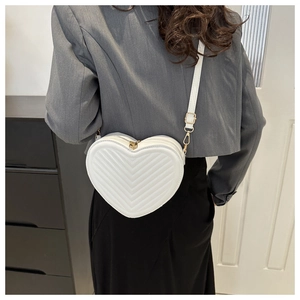 Rear view of model wearing a white heart-shaped crossbody bag with V-quilt stitching
