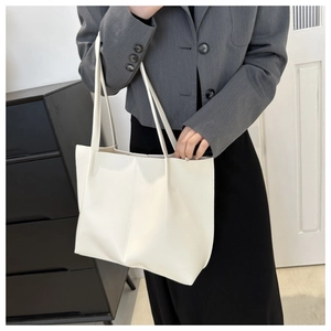 Detailed view of large cream-colored tote bag in soft leather with long shoulder straps