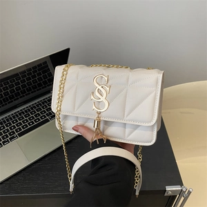 Borsa a tracolla trapuntata bianca con logo S dorato e catena in un contesto d'ufficio