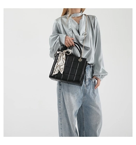Detail of black checkered leather tote bag with elegant silk scarf wrap and chain strap