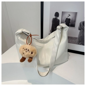 Detailed view of white faux leather tote bag with a soft brown plush monster pendant