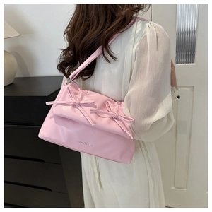 Detailed view of a pink bow shoulder bag with pleated PU texture and fashion lettering