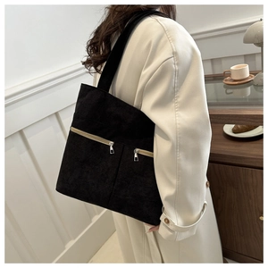 Detail of black corduroy tote bag with dual zipper pockets worn by a model in casual setting