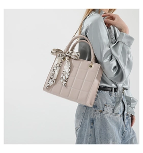 Detail of pink quilted handbag with silk scarf handle and golden chain strap