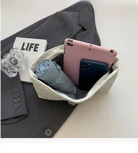 Top view of spacious interior of white quilted chain bag holding tablet and umbrella