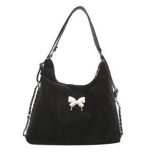 Black suede shoulder bag featuring modern white liquid-style bow and metal chain straps
