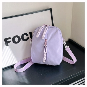 Détail du sac bandoulière en nylon lilas avec des tirettes de fermeture tressées