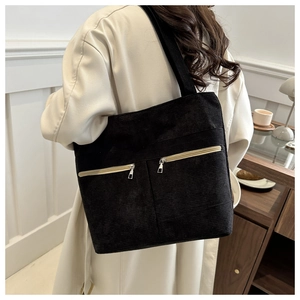 Detail of black corduroy tote bag with dual front zipper pockets and wide shoulder strap