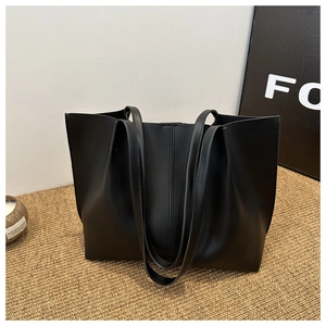 Close-up of minimalist black tote bag featuring vertical stitching and matte leather texture