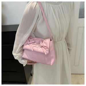Detailed view of pink shoulder bag with double bow decoration and slim strap