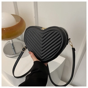 Detail of black heart-shaped handbag with V-quilted texture and gold zipper hardware