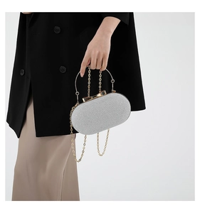 Detail of silver glitter evening clutch with gold metal handle and chain strap on model