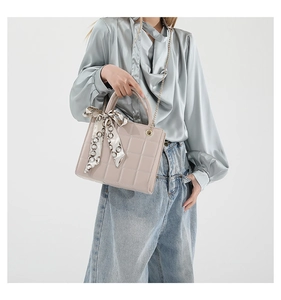 Detail of quilted crossbody bag with silk scarf handle on a grey silk shirt outfit
