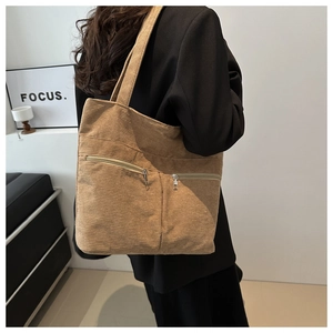 Detail of khaki corduroy tote bag with dual front zippers shown on a shoulder