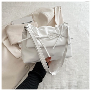 Detail of white pleated cloud bag with double bows and Fashion & Bags text on leather
