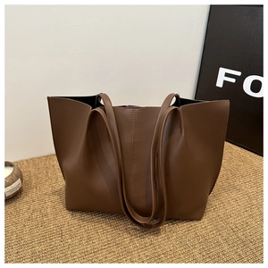 Detail view of large dark brown leather tote bag with vertical stitching and thin straps
