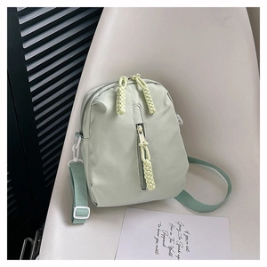 Detail of light green nylon shoulder bag featuring unique yellow woven zipper pullers
