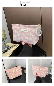 Pink canvas cosmetic bag with white heart patterns and elegant pearl zipper handle