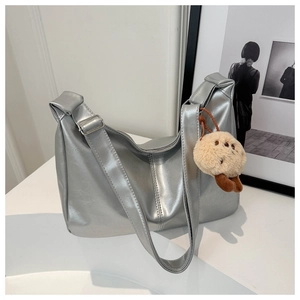 Detail of silver metallic underarm bag with plush biscuit pendant and adjustable strap